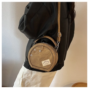 Brown denim round crossbody bag detail showing side view with rivet and brand label