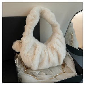 Detailed view of white faux fur dumpling bag with pearl charm in a luxury black gift box