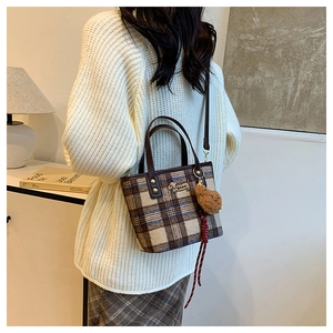 Detail of plaid woolen tote bag featuring dachshund embroidery and plush bear charm