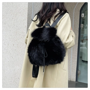Detail of black faux fur drawstring backpack with soft texture on a model outfit