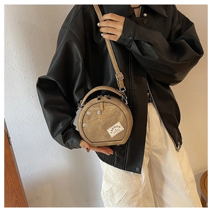 Detail of khaki round crossbody bag featuring denim pocket design and fashion label