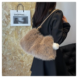 Detailed shot of brown faux fur shoulder bag with white pompom charm on slim strap