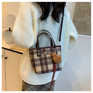 Close-up of wool plaid crossbody bag with dachshund embroidery and teddy bear charm