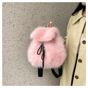 Detailed texture of pink faux fur drawstring backpack with black straps held by hand
