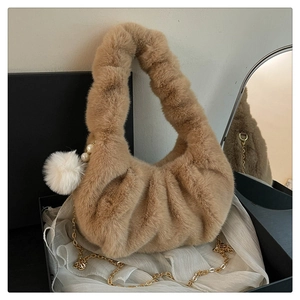 Detail of plush dumpling bag in coffee brown with pearl pompom and gold chain strap