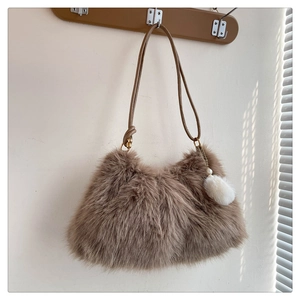 Detail of plush brown faux fur hobo bag with soft texture and white pompom charm