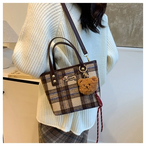 Plaid wool shoulder bag with dog patch embroidery and brown bear pendant shown on model