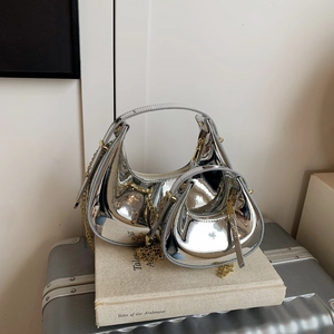 Silver patent leather crescent handbag set with gold chain strap on books