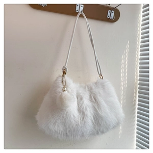 Detail of white plush shoulder bag with pearl and pom-pom charm accent