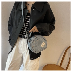 Detail of light blue denim round crossbody bag featuring fashion label and creative pocket