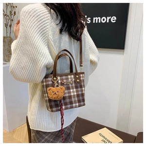 Detail of checkered shoulder bag with dachshund embroidery and a plush bear charm