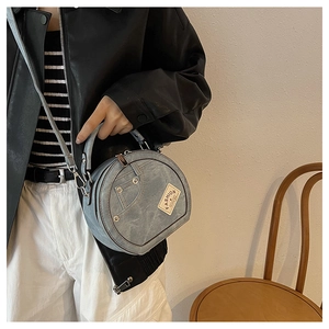 Detail of light blue denim crossbody bag with FASHION label and metal studs