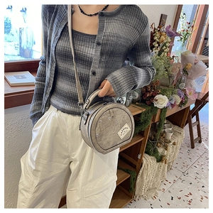 Detail of round grey denim crossbody bag featuring a unique fashion pocket design