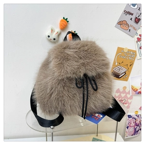 Detail of soft brown faux fur backpack with black drawstring closure and cute charms