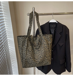 Close-up of leopard print canvas tote bag hanging on a rack with natural light shadows