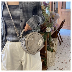 Detailed view of grey denim cylinder bag featuring fashion label and adjustable strap