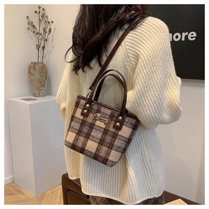 Detail of plaid wool tote bag showing leather strap and dog logo in casual setting