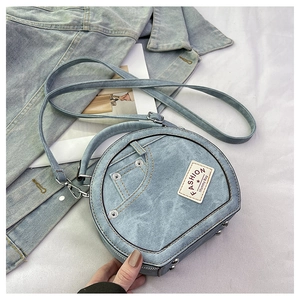 Close-up of circular blue denim crossbody bag with metal rivets and fashion label