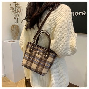 Close-up of a plaid woolen crossbody bag with dachshund patch and leather straps