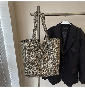 Close-up of leopard print canvas tote bag with wide strap on a clothing rack