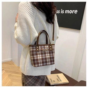 Detail of checkered tote bag with dachshund patch, leather handles and gold rivets