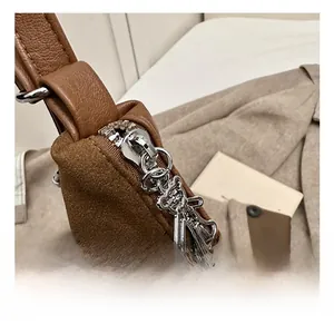 Detail of brown suede tote with a cute silver bear-shaped metal zipper pull accessory