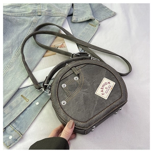 Detail of grey denim crossbody bag featuring contrast yellow stitching and silver rivets