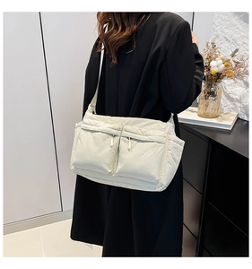 Détail d'un grand sac bandoulière en nylon matelassé ivoire avec deux poches zippées