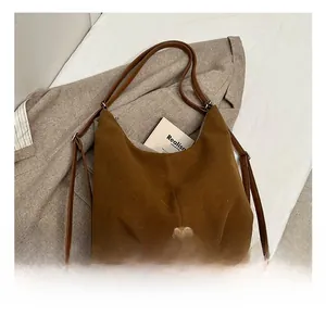 Brown suede hobo bag with silver metallic clasp and shoulder strap on a chic blazer background