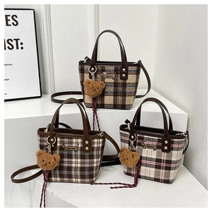 Detail of plaid woven tote bag with cartoon dog patch and plush teddy bear charm