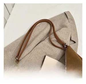 Detail of brown suede tote bag with metal zipper closure and matching leather shoulder strap