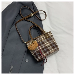 Detail of checkered shoulder bag with dachshund embroidery and brown teddy bear charm