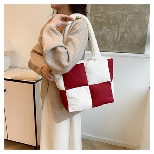 Detail of red and white checkered quilted tote bag worn by a model in a modern interior