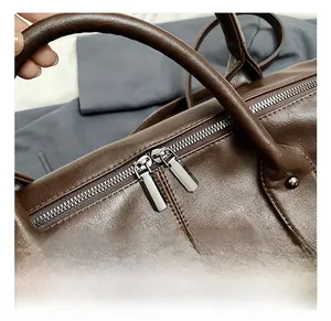 Detail of brown faux leather tote bag featuring double metal zippers and fine stitching