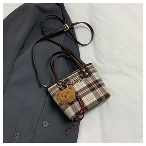 Detail of plaid shoulder bag with puppy embroidery and plush bear charm