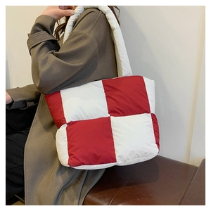 Detailed view of red and white checkered quilted tote bag worn over the shoulder