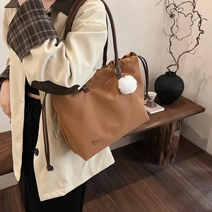 Brown large capacity tote bag with dark leather straps and white plush pendant for women