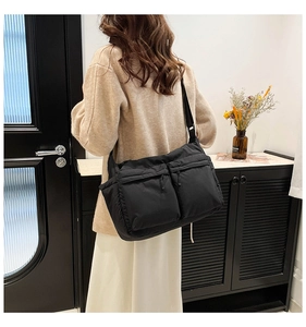 Détail du sac à bandoulière en nylon noir avec plusieurs poches zippées fonctionnelles