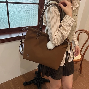Brown large capacity tote bag with drawstring detail and plush charm shown on model