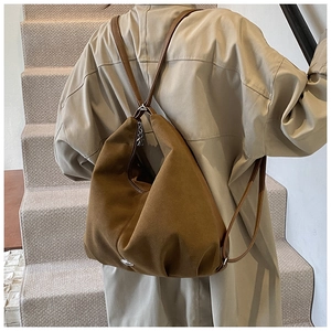 Brown suede-texture backpack and tote bag shown worn on a khaki trench coat