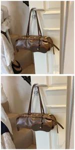 Close-up of brown baguette bag with metal buckles and detachable glasses pouch accessory
