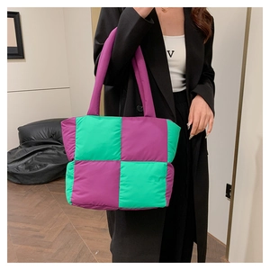 Detailed view of the purple and green oversized quilted puff tote bag on a model shoulder