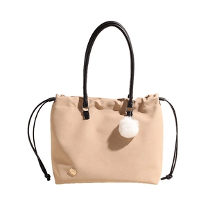 Minimalist apricot tote bag with black handles, drawstring detail and a plush charm
