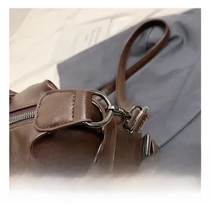 Detail of dark brown leather underarm bag with gunmetal ring hook and silver zipper track