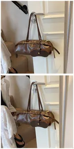 Detail of dark brown baguette bag in glossy leather with detachable coin purse and metal buckles