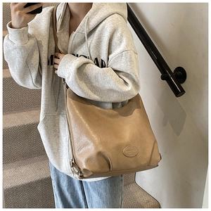 Detail of vintage suede tote bag with embossed oval logo patch in camel brown finish