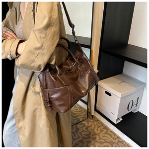 Detail of dark brown leather tote bag with side buckle and adjustable shoulder strap