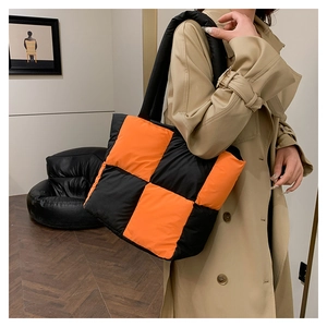 Macro detail of high-contrast black and orange quilted tote bag with padded texture