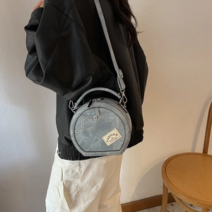 Stylish blue denim round crossbody bag with fashion label and adjustable shoulder strap