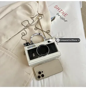 Creative camera-shaped crossbody bag shown next to an iPhone 12 for size comparison